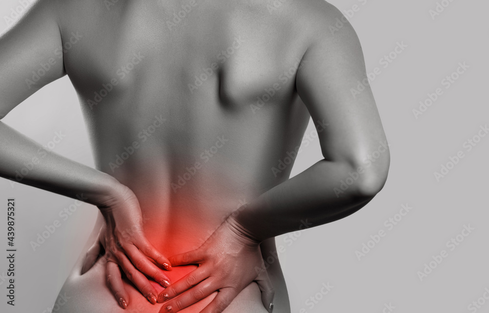 Naklejka premium Woman having backache, pain back isolated on gray background. Scoliosis. Spinal cord problems on womans back. monochrome photo with red as a symbol for the hardening