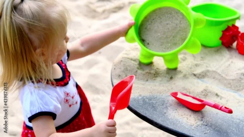 child plays in summer with sand on seashore, in the sandbox, on playground, concept of development of fine motor skills, build sand castles, summer vacation, fun on beach, summer vacation