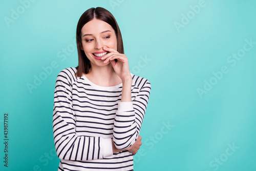 Photo of cheerful flirty lady hand chin look empty space wear striped shirt isolated on turquoise color background
