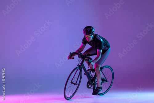 Fototapeta Naklejka Na Ścianę i Meble -  Cyclist riding a bicycle isolated against neon background