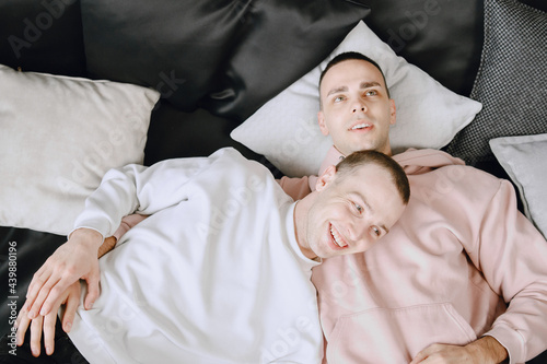 Happy gay couple lying on bed at home