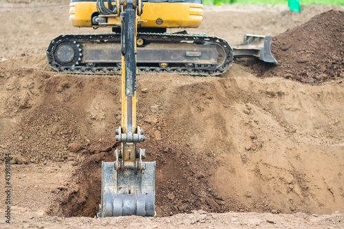 A mini excavator is digging the soil in the field.