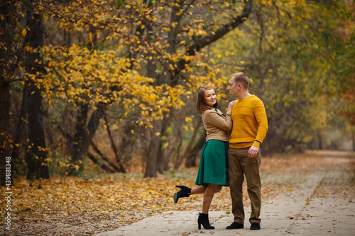 Happy couple on autumn walk outdoors. Two lovers in autumn park. Love and tender touch. Gentle hugs. Young man and woman in classic autumn colors outfit on a romantic date in a cozy park © Olga Mishyna