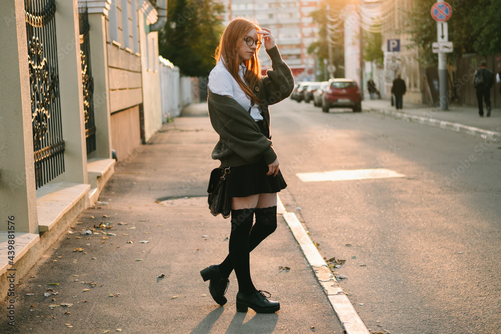 beautiful red-haired woman in a green sweater in the city at sunset. beautiful red-haired woman in a green sweater in the city at sunset.