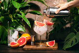 Pink grapefruit and rosemary gin cocktail is poured in prepared gin glass