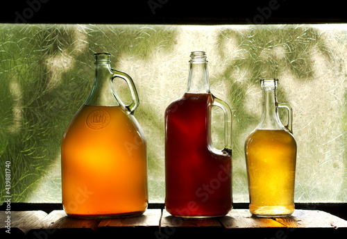 Glass bottles of fermented kombucha tea with peach, оrange, cherry  on the window 