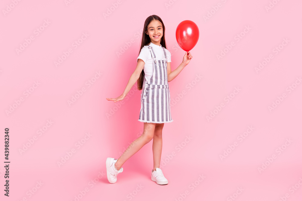 Full length body size photo schoolgirl keeping red air balloon isolated pastel pink color background Full length body size photo schoolgirl keeping red air balloon isolated pastel pink color background