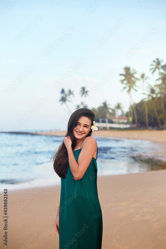 Beautiful smiling young woman in green dress on beach over sea and blue sky background. Summer vacation, travel Beautiful smiling young woman in green dress on beach over sea and blue sky background. Summer vacation, travel