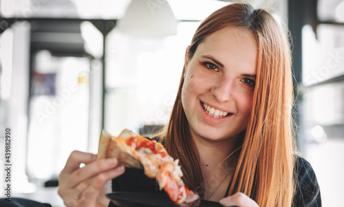 young teenager redhead girl eating pizza in cafe
