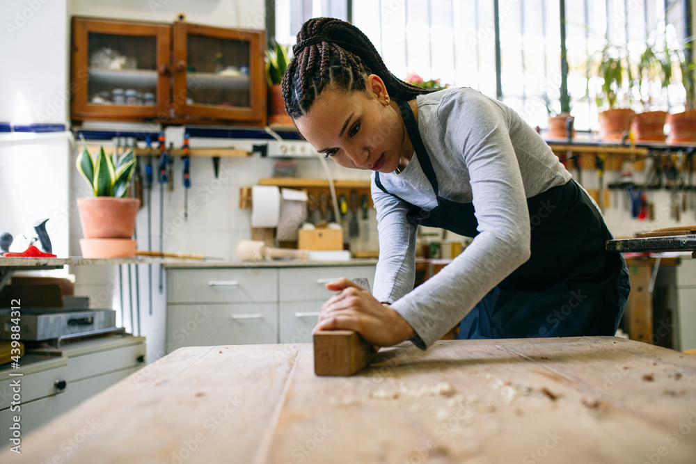 Female carpenter working with plane in workshop 