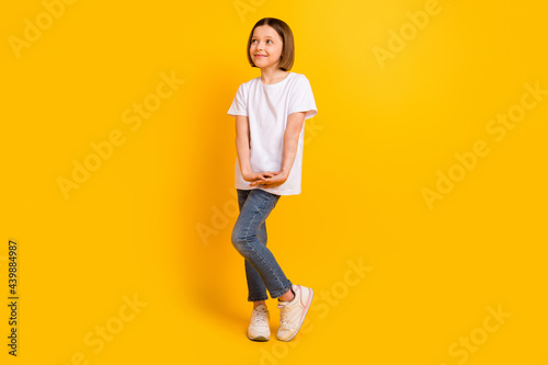 Full length body size photo schoolgirl in casual clothes smiling looking copyspace isolated vibrant yellow color background