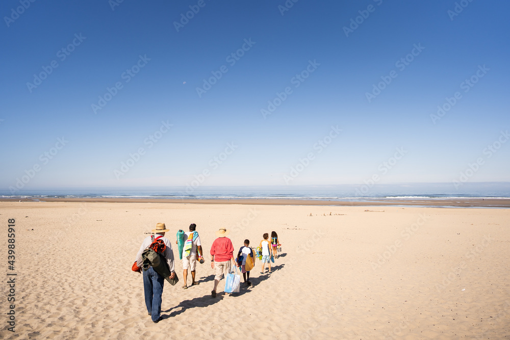 Multigenerational family walks across sandy beach Multigenerational family walks across sandy beach