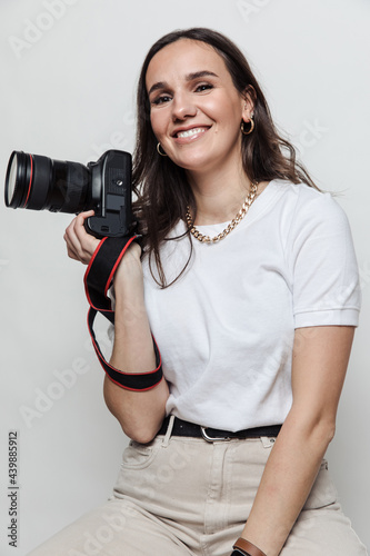 Woman photographer holding a camera in studio