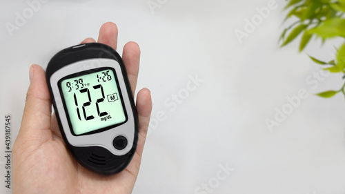 hold a diabetic glucose meter to check high blood sugar levels high blood sugar, white background