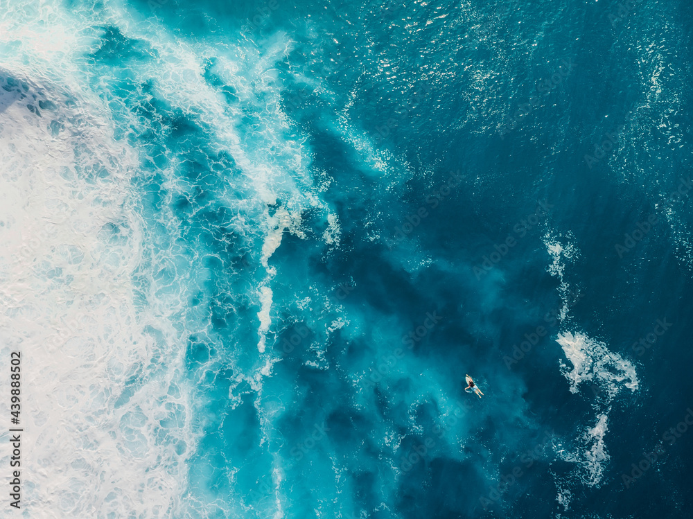 Blue ocean with waves and foam. Aerial view with surfer and sea
