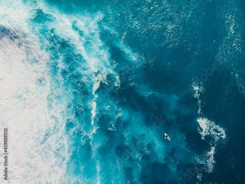 Blue ocean with waves and foam. Aerial view with surfer and sea