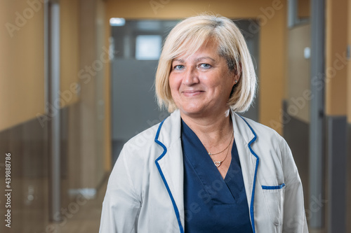 Happy real senior medic woman standing in hospital corridor