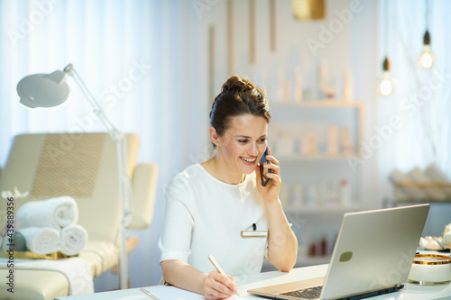 happy woman worker in beauty salon talking on phone photo