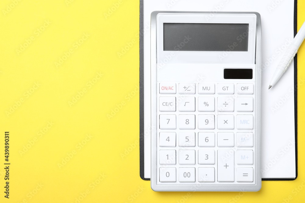 Calculator, clipboard and pen on yellow background, top view. Space for text Calculator, clipboard and pen on yellow background, top view. Space for text