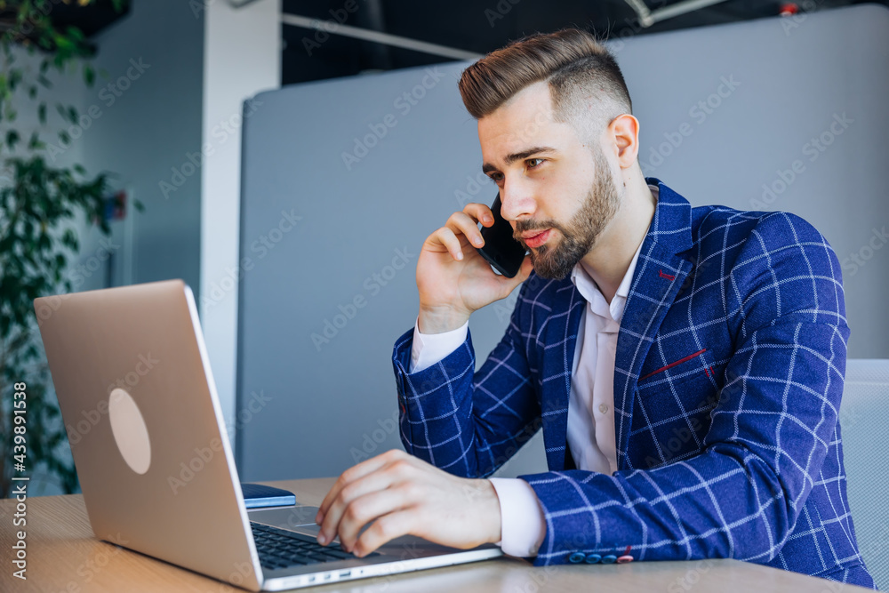 Serious male businessman working at office desk, using mobile phone and laptop computer, typing, making a phone call. Serious male businessman working at office desk, using mobile phone and laptop computer, typing, making a phone call.
