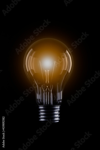 Light bulb with bright orange light on a black scene