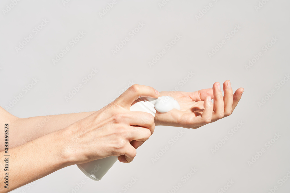 Woman putting foamy cosmetic product on hand Woman putting foamy cosmetic product on hand