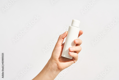 Woman with plastic bottle of cosmetic product photo