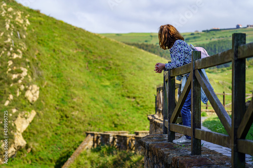 Woman looking at the green field landscape from a lookout point. Santander. photo