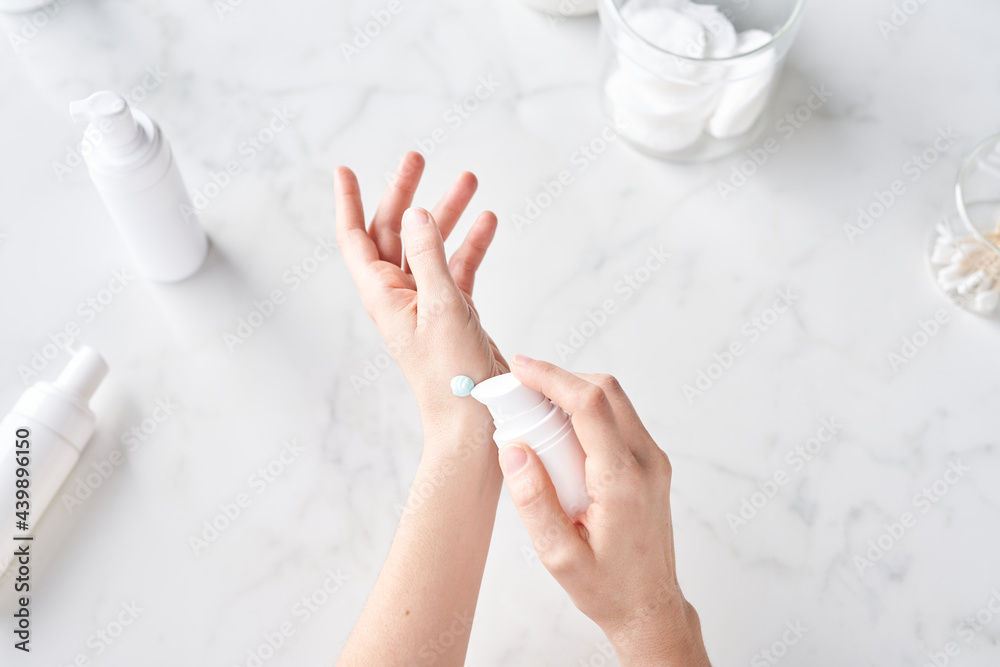© Martí Sans/Stocksy - Woman applying cream on hand.