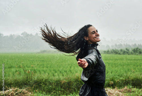 A young woman joyfully spinning in the rain photo