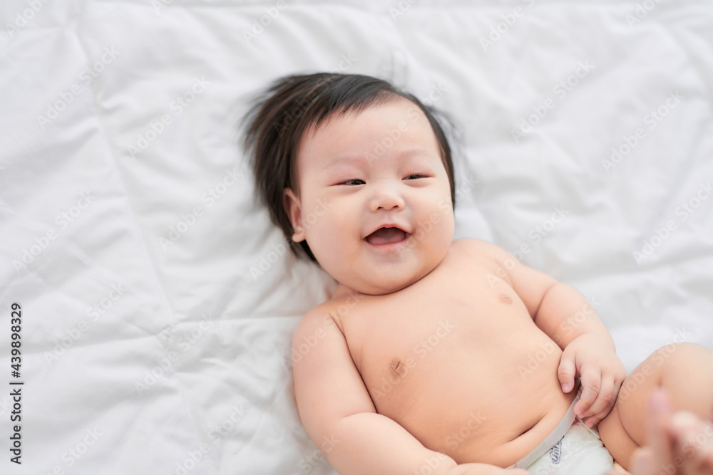 Happy family. Mother tickling her laughing baby, playing in bed at home Happy family. Mother tickling her laughing baby, playing in bed at home