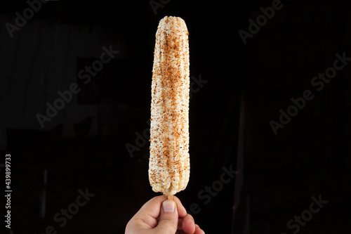 mexican boiled white corn on the cob with chili, lime and mayonnaise on black background photo