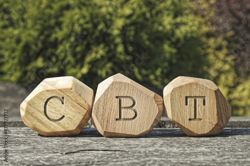 Letters CBT written on wooden irregular blocks. Cognitive behavioral therapy trauma treatment concept. photo