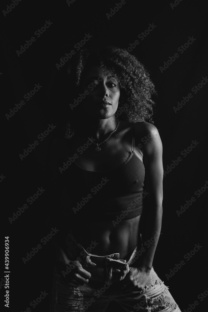Stylish black woman standing in dark studio Stylish black woman standing in dark studio