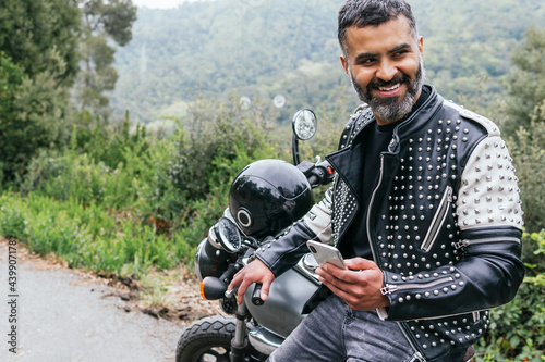 Stylish male biker browsing smartphone in nature