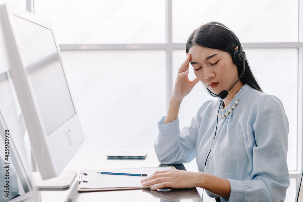 Call center operators provide advice and counseling to help clients with stressful gestures, operators are having a headache and use their hands to touch their heads with a tired expression. Call center operators provide advice and counseling to help clients with stressful gestures, operators are having a headache and use their hands to touch their heads with a tired expression.