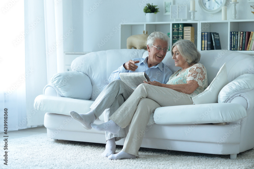 Close-up portrait of a  senior couple with newspaper  at home