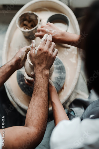 Photo from above. Male and female hands in a pottery workshop make vases from clay