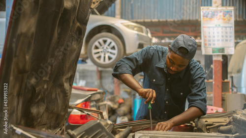 African maintenance male checking car, service via insurance system at Auomobile repair and check up center