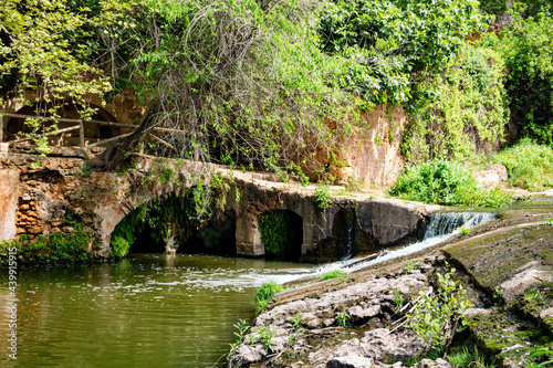 Beautiful view of a waterfall in a river next to molino del algarrobo in alcala de guadaira. Spring season, vivid natural colors, leafy trees, summer vibes. Tourism point.
