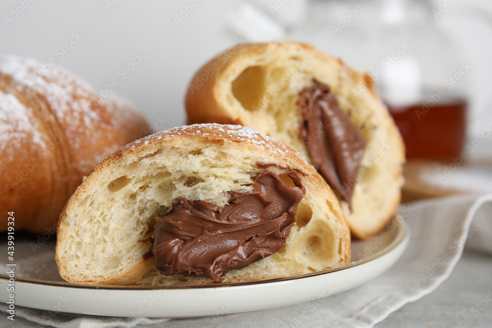 Tasty croissants with chocolate and sugar powder on plate, closeup Tasty croissants with chocolate and sugar powder on plate, closeup