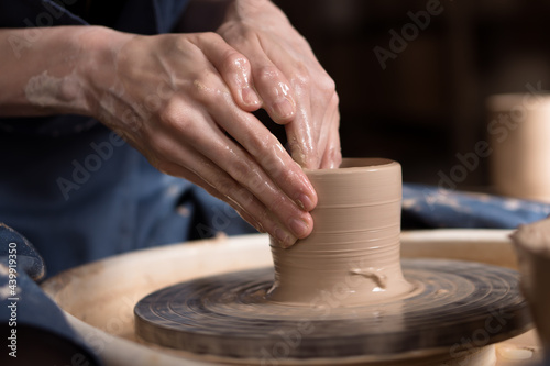 hands of a potter working with clay and pottery wheel