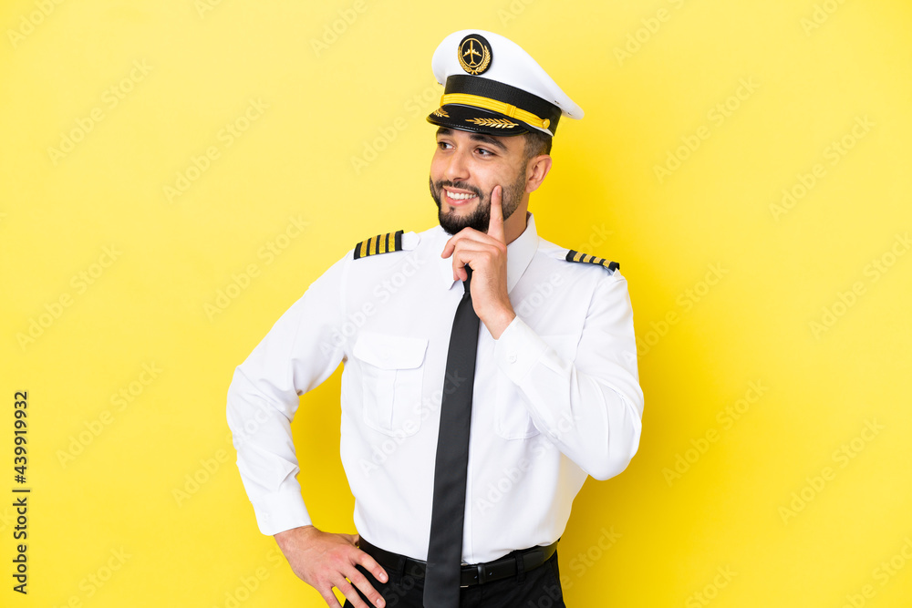 Airplane arab pilot man isolated on yellow background thinking an idea while looking up Airplane arab pilot man isolated on yellow background thinking an idea while looking up