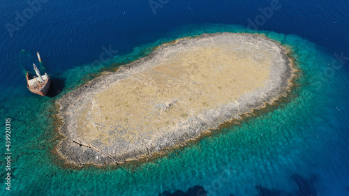 Fototapeta Naklejka Na Ścianę i Meble -  Aerial drone photo of half sunk ship in small islet left to rust