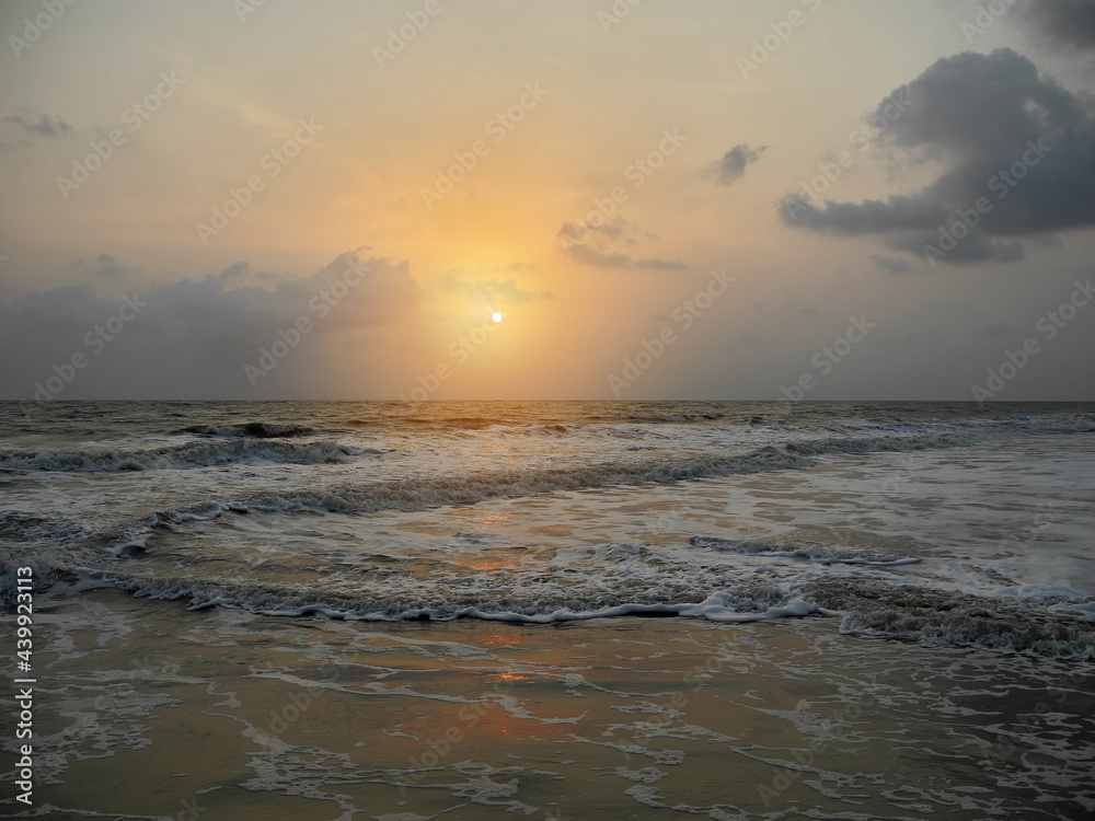 Obraz premium Sunset on the background of the dark gray foaming waves of the Arabian Sea. India, Kerala, Cochin