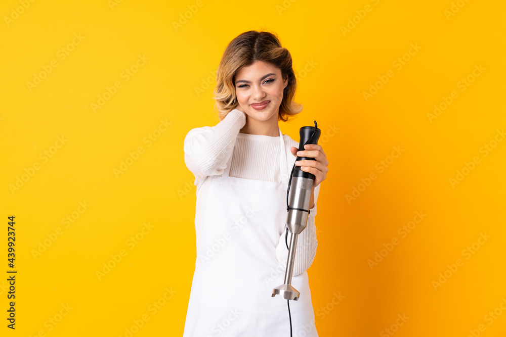 Girl using hand blender isolated on yellow background laughing Girl using hand blender isolated on yellow background laughing