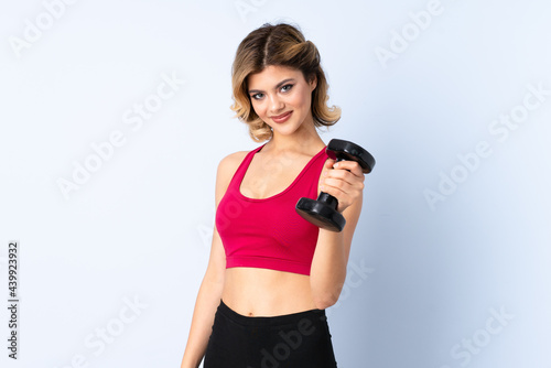 Teenager Russian girl making weightlifting isolated on blue background with happy expression