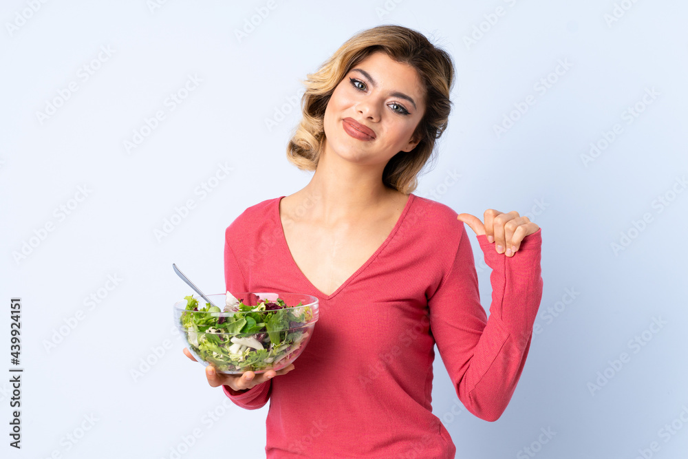 Teenager woman with salad isolated on blue background proud and self-satisfied Teenager woman with salad isolated on blue background proud and self-satisfied