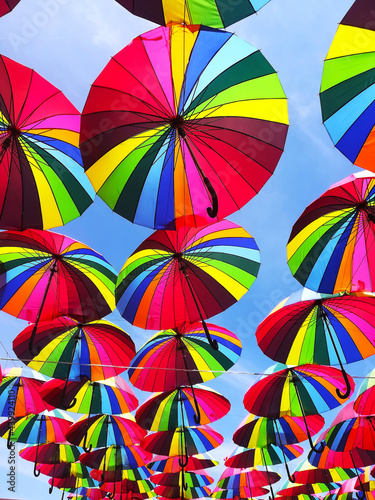 saturated colorful umbrellas against the blue sky hang overhead 