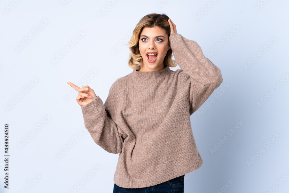 Young Russian woman isolated on blue background surprised and pointing finger to the side Young Russian woman isolated on blue background surprised and pointing finger to the side